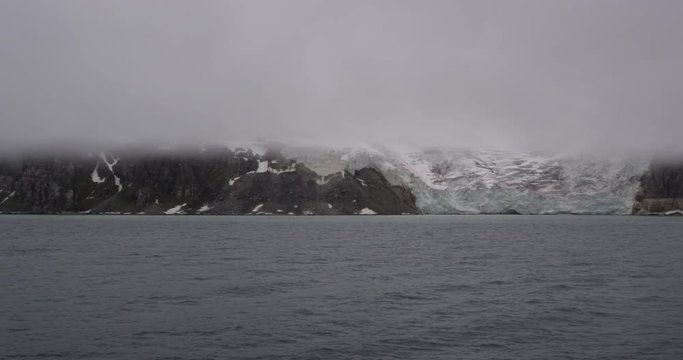 Pan of Glacier in Mountains Covered in Clouds