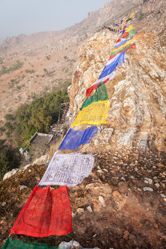 Lungta (horse of wind) - the Tibetan prayful flags, over a mountain ridge with Mahakala's cave, the place where Siddhartha Gautama have spent some time in an ascesis.  