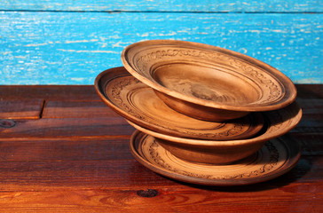 Four round empty brown clay plate bowl with ornament pattern on wooden background. Ukraine