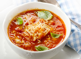 Homemade tomato soup sprinkled with cheese and basil in a bowl