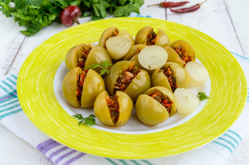 Pickled green tomatoes, stuffed with a mixture of chopped garlic, parsley, chili pepper. Spicy appetizer on a white background. Close up