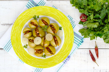 Pickled green tomatoes, stuffed with a mixture of chopped garlic, parsley, chili pepper. Spicy appetizer on a white background. The top view