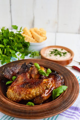 Fried wings (duck, chicken) in a honey glaze in a clay bowl on a light background.