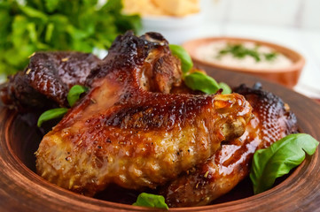 Fried wings (duck, chicken) in a honey glaze in a clay bowl on a light background.  Close up