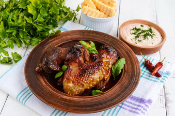 Fried wings (duck, chicken) in a honey glaze in a clay bowl on a light background.
