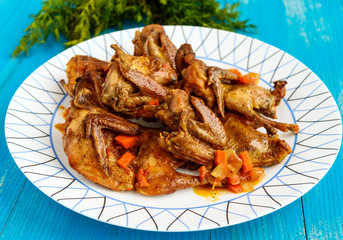 Quail stew with vegetable gravy on a blue wooden table.