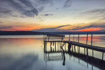 Fototapeta na wymiar Beautiful long exposure sunset view with bench on wooden bridge