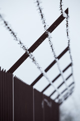 High fence and barbed wire with ice crystals