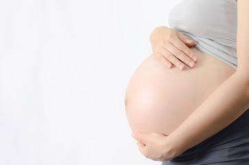 Close-up Image of pregnant woman touching her belly with hands on white background