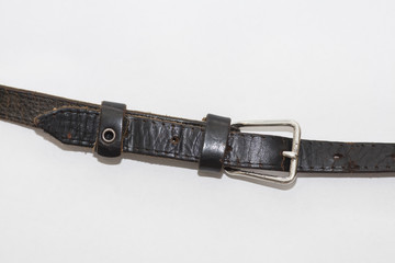 Old leather belt with a buckle on a white background. Close up, selective focus
