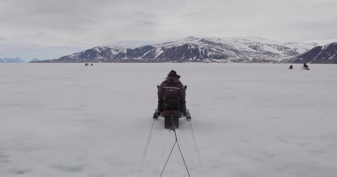 View of guides on snow machine pulling komatik across sea ice