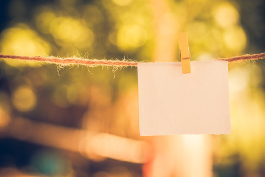 Blank white paper and clippaper  hanging on the clothesline with bokeh nature background.Designer concept.vintage or retro tone.