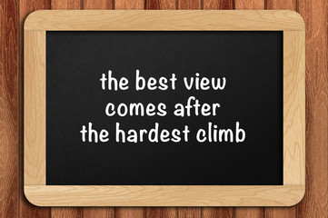 Inspirational motivating quote on chalkboard with wooden background. the best view comes after the hardest climb
