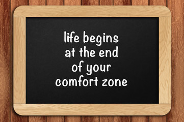 Inspirational motivating quote on chalkboard with wooden background. life begins at the end of your comfort zone