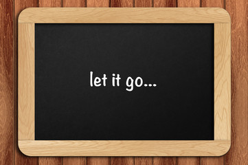 Inspirational motivating quote on chalkboard with wooden background. let it go
