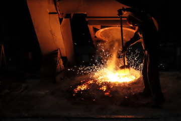 Foundry worker melting metal for casting spare parts. - obrazy, fototapety, plakaty