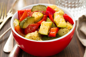 baked vegetables in red bowl on wooden background