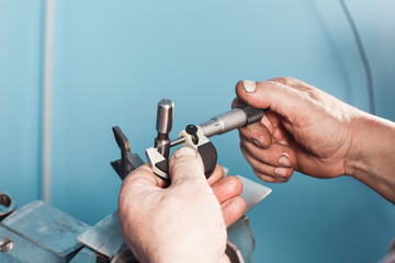 mechanical technician worker hands measuring detail tool after processing at workshop with sliding caliper manufacturing