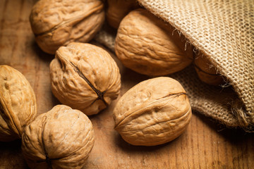 Nueces sobre mesa de madera y bolsa de arpillera vista de cerca