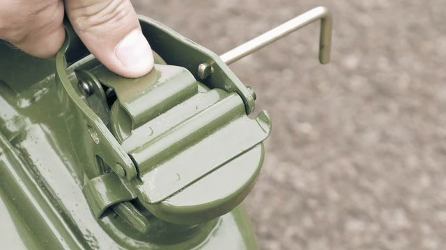 Man opens gas petrol or diesel jerry can with fuel and spills it on the ground.