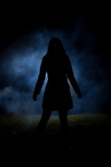 spooky silhouette girl at night with smoke in background
