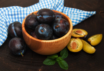 Bowl with  plums with green leaves
