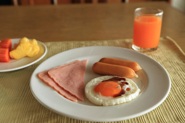 Set of american breakfast on table, fried egg, ham, and sausage