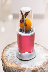Close view of a blender with an orange and cinnamon sticks on a