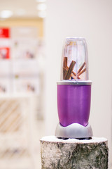 Close view of a blender with cinnamon sticks on a snowy log