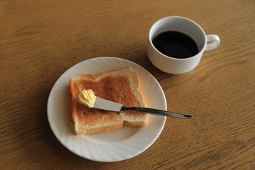 Breakfast, plate of  toast with butter and cup of black coffee.