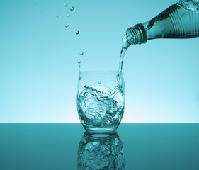 Bottle with creative splashing water in the glass