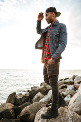 Young man walking on the beach while listening music