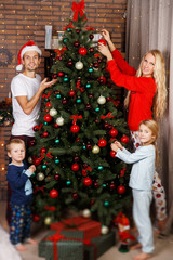 Parents with children decorates pine