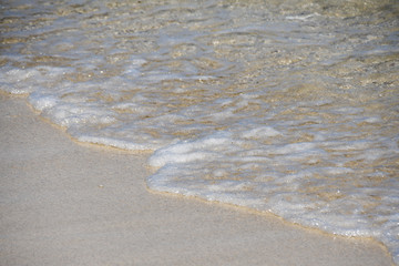 Waves crashing on sandy beach in close up