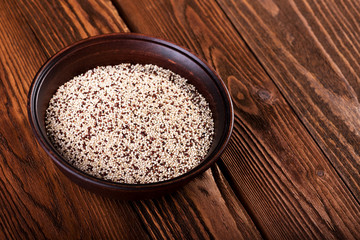 Groats quinoa in ceramic bowl on wooden background