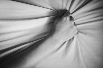 young woman in bed clutching tightly her Bed linen
