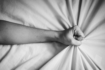 young woman in bed clutching tightly her Bed linen