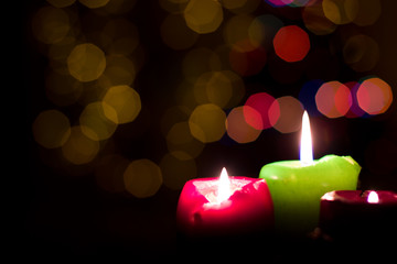 Three candles on a Christmas tree background.