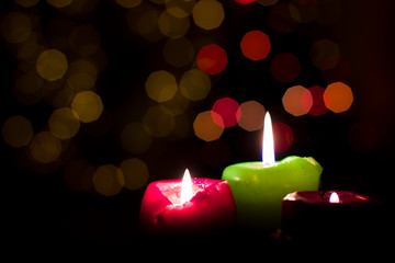 Three candles on a Christmas tree background.