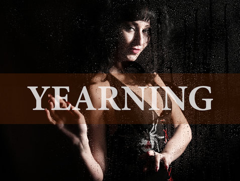 yearing written on virtual screen. hand of young woman melancholy and sad at the window in the rain.