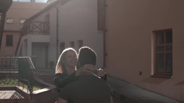 A couple in love swirling around, smiling, kissing at the sunset in city, slow mo