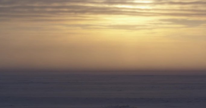 Empty tundra in sunset blizzard with sun ice and blowing snow