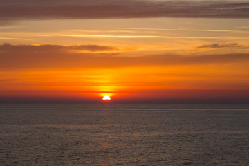Sunset at sea with sun, clouds and horizon