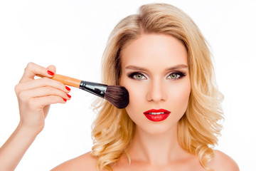 Attractive young blonde with red lips applying powder with brush