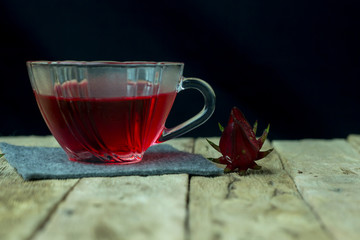 Glass of cold roselle juice - healthy food against wood