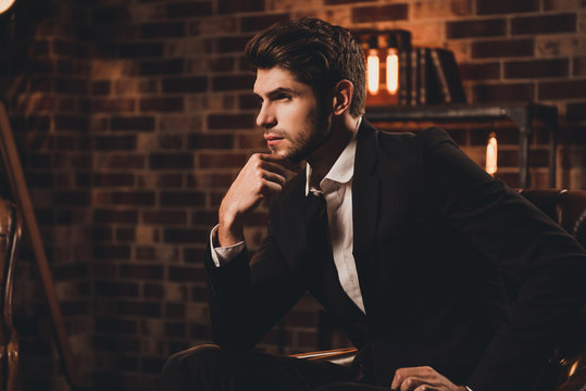 Portrait of ponder man in suit  sitting on couch and touching ch