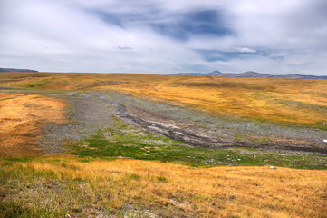 Valley of the mountain river among meadows with dry yellow grass on the highland steppe near Mongolia, Plateau Ukok, Altai, Siberia, Russia