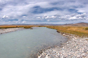 White wide river under white clouds and blue sky, Plateau Ukok, Altai mountains, Siberia, Russia