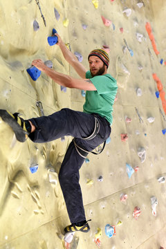 Bouldersport: Sportler klettert in einer Halle an einer künstlichen Kletterwand
