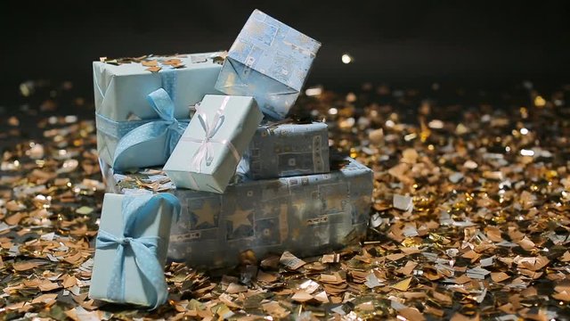 Gold confetti falling on blue gifts boxes
